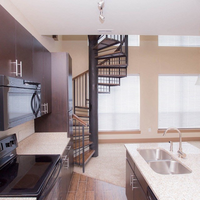 a kitchen with a sink and stove and a spiral staircase in the background