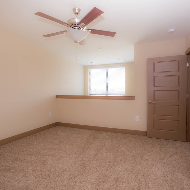 an empty room with a ceiling fan and a window