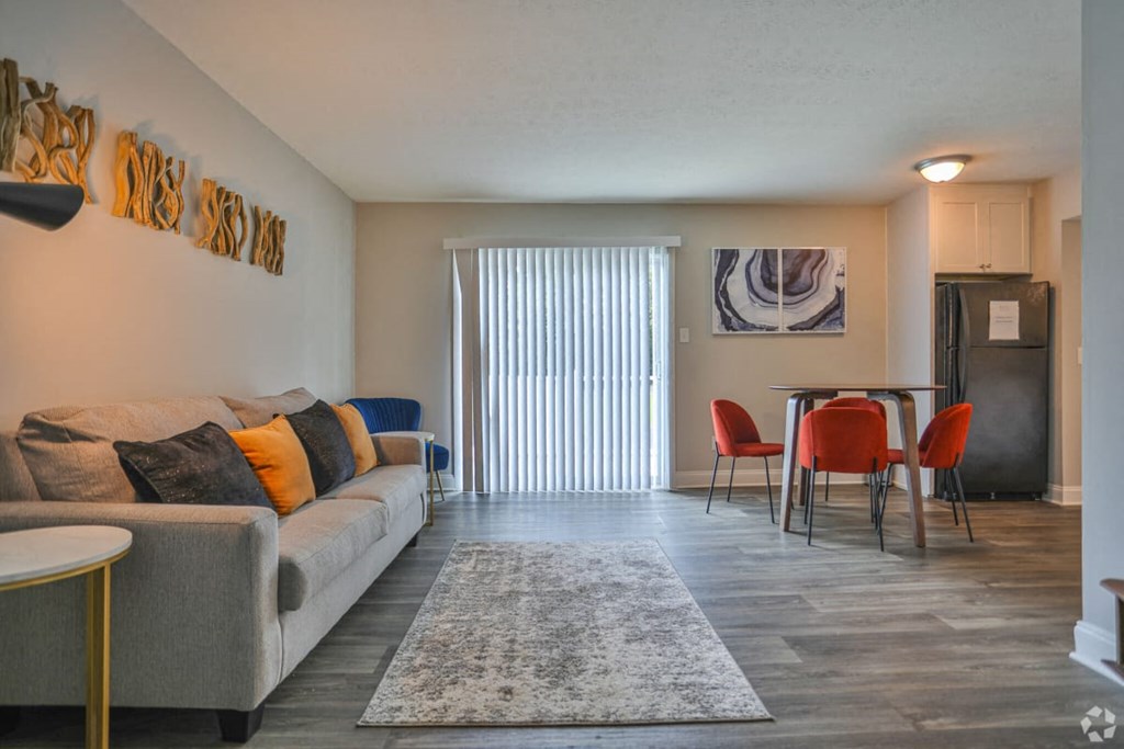 a living room with a couch a table and chairs and a sliding glass door