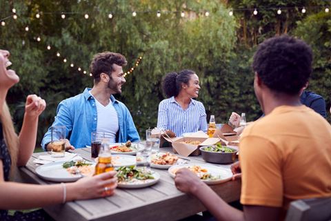 group of people sitting around a picnic table eating food