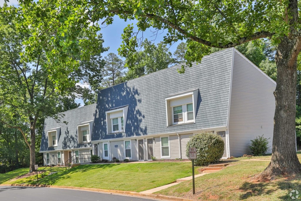 a gray house with a blue roof and a green lawn