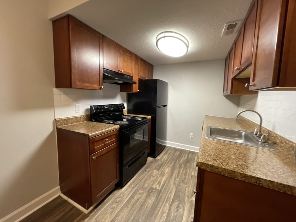 a kitchen with a black stove top oven next to a sink and a refrigerator