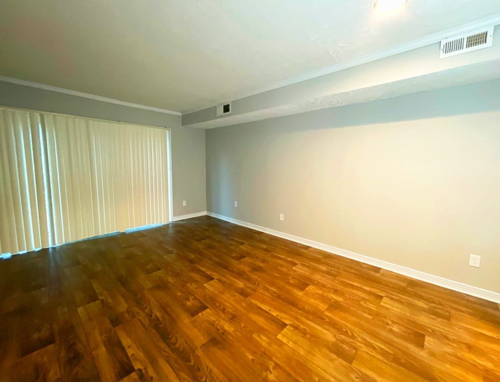 a bedroom with hardwood floors and a large window