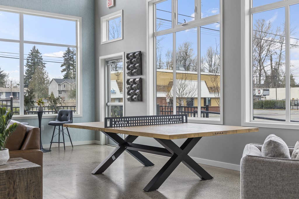 a ping pong table in the clubhouse with large windows,