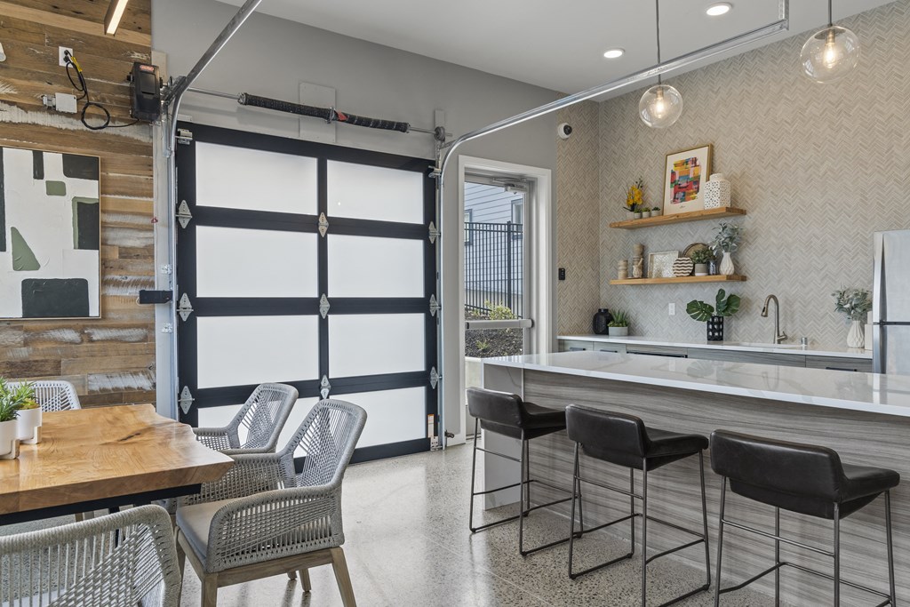 a kitchen area with a bar and chairs,