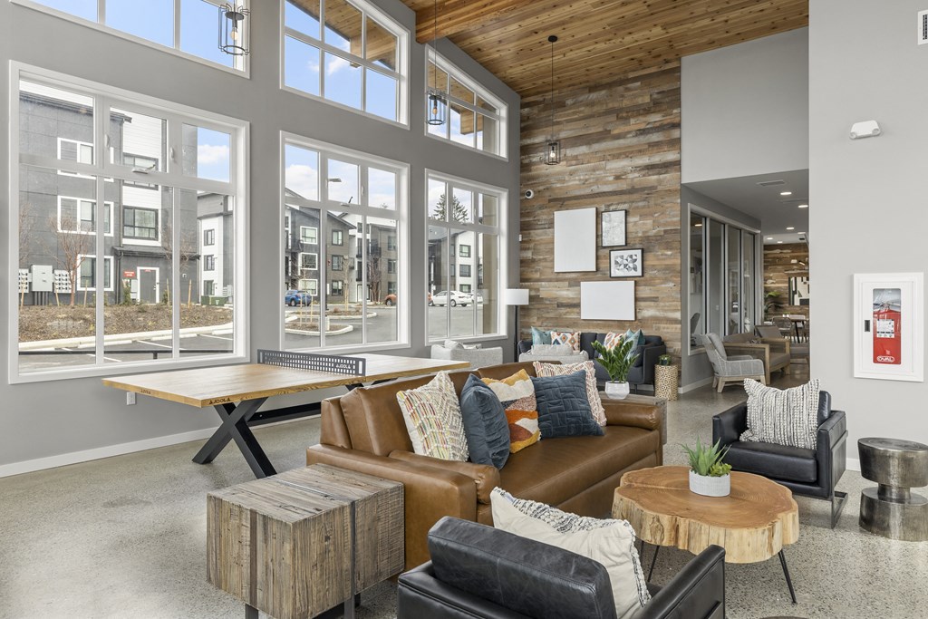 clubhouse with a brown leather couch and a wooden coffee table in front of a large window,