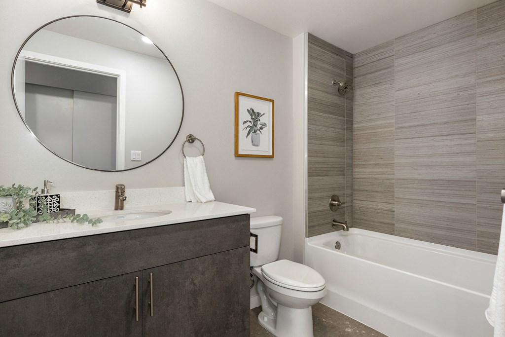 a bathroom with a white toilet next to a white bathtub,