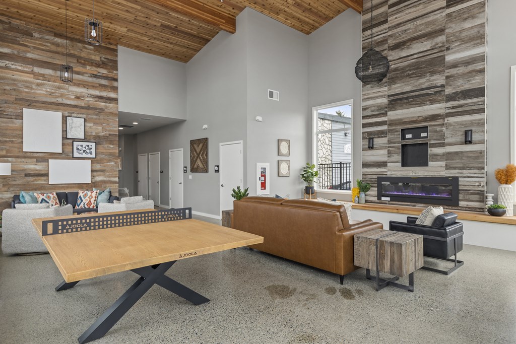 Apartments in Tacoma, WA - Pacific Ridge - clubhouse with ping-pong table, seating area, fireplace, and large windows,