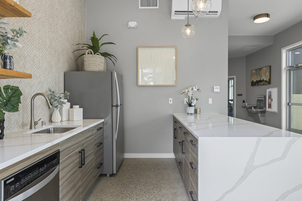 a kitchen with white countertops and a stainless steel refrigerator,