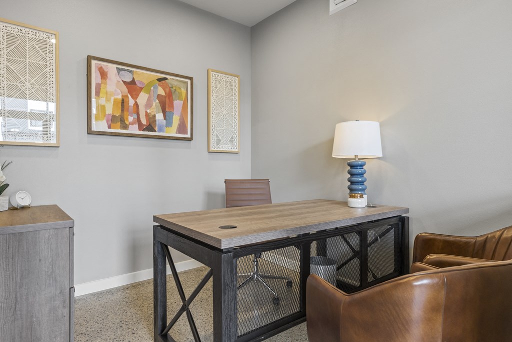 a desk with a lamp and a chair in a room with paintings on the wall,