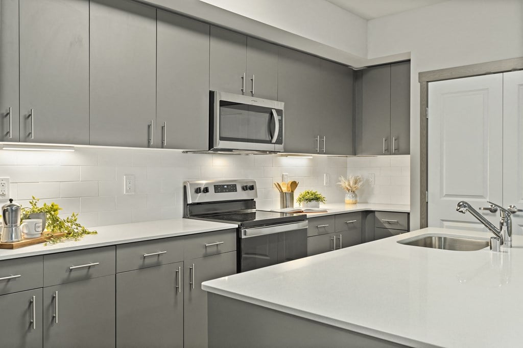 a kitchen with gray cabinets and white countertops,
