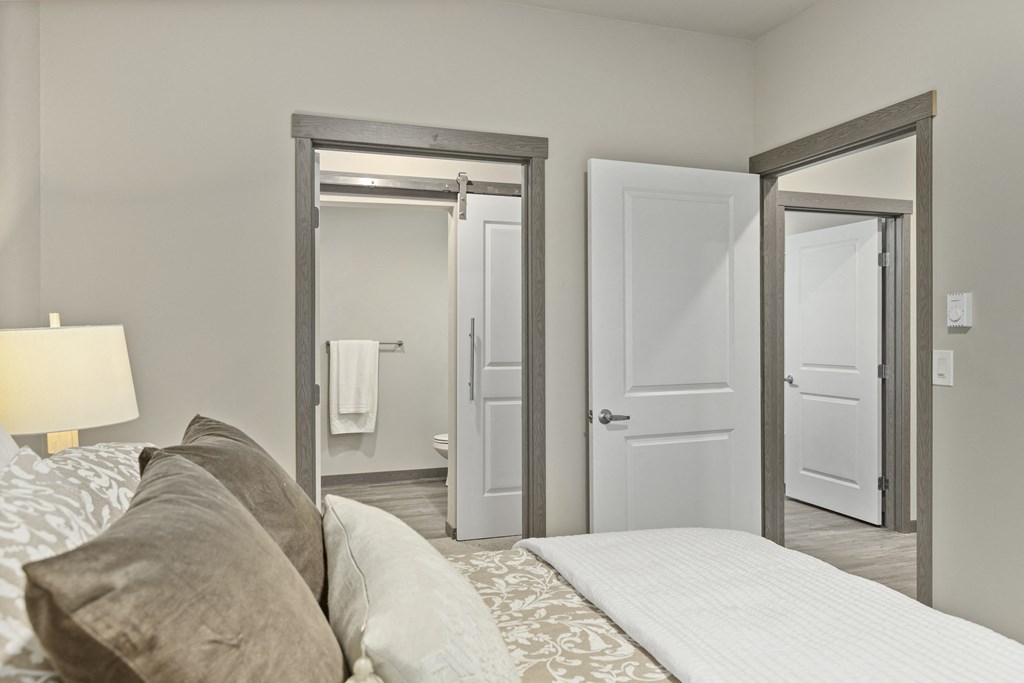 a bedroom with a large bed and a door to a bathroom with a towel rack,