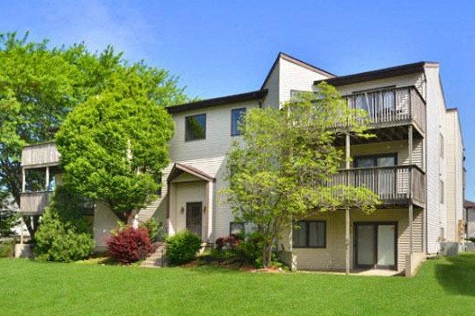 an apartment building with green grass and trees
