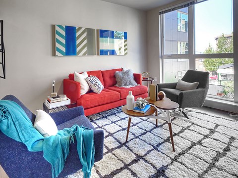 a living room with a red couch and a blue rug