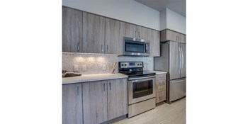 Tigard OR Apartments - Spacious Kitchen with Stylish Interior and Modern Amenities Such as Fridge, Microwave, and Stove - Photo Gallery 28