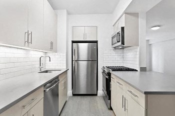 Apartments for Rent Upper East Side New York - Bright Kitchen with Stainless Steel Appliances, Tiled White Backsplash, and Wood-Inspired Flooring - Photo Gallery 6
