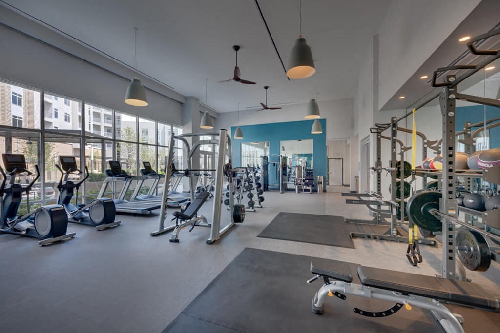 a gym with weights and cardio equipment and windows
