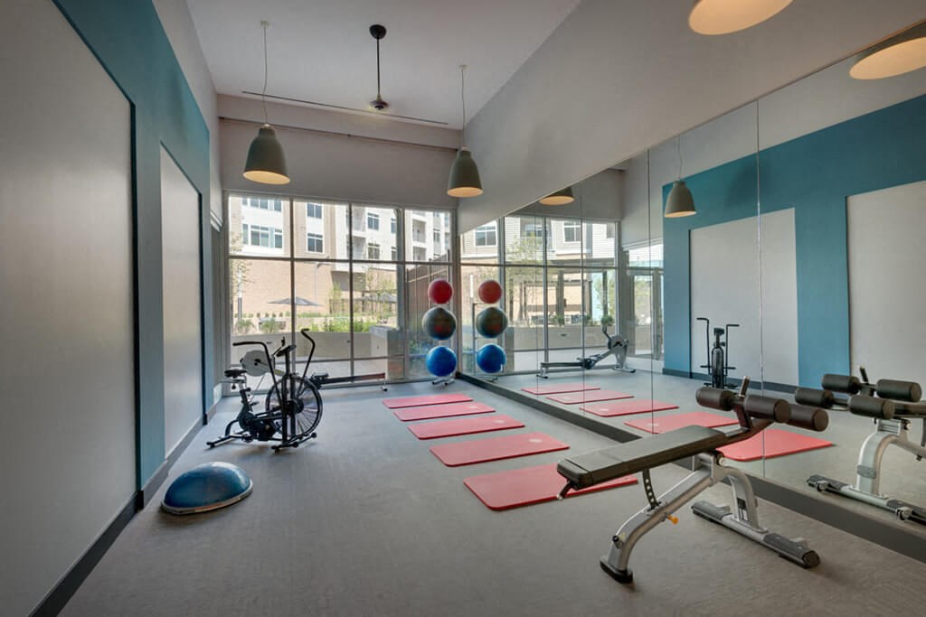 a workout room with yoga mats and exercise equipment in a building with windows