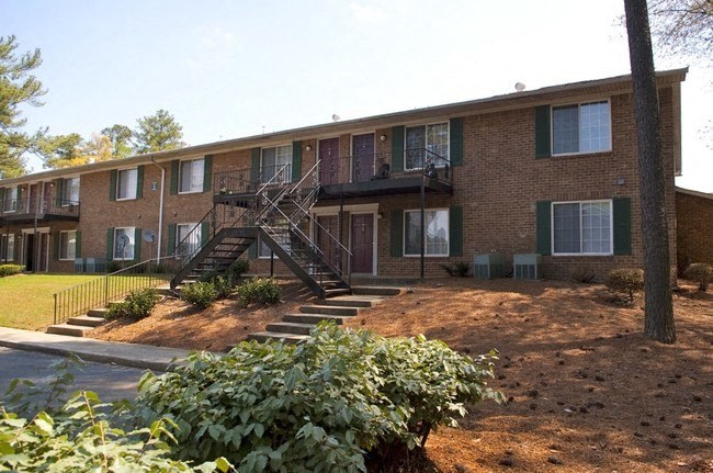 Three-Bedroom Townhomes in College Park, GA - Beacon Ridge - Brick Apartment Building Exterior with Landscaping, Windows with Green Shutters, and Balconies