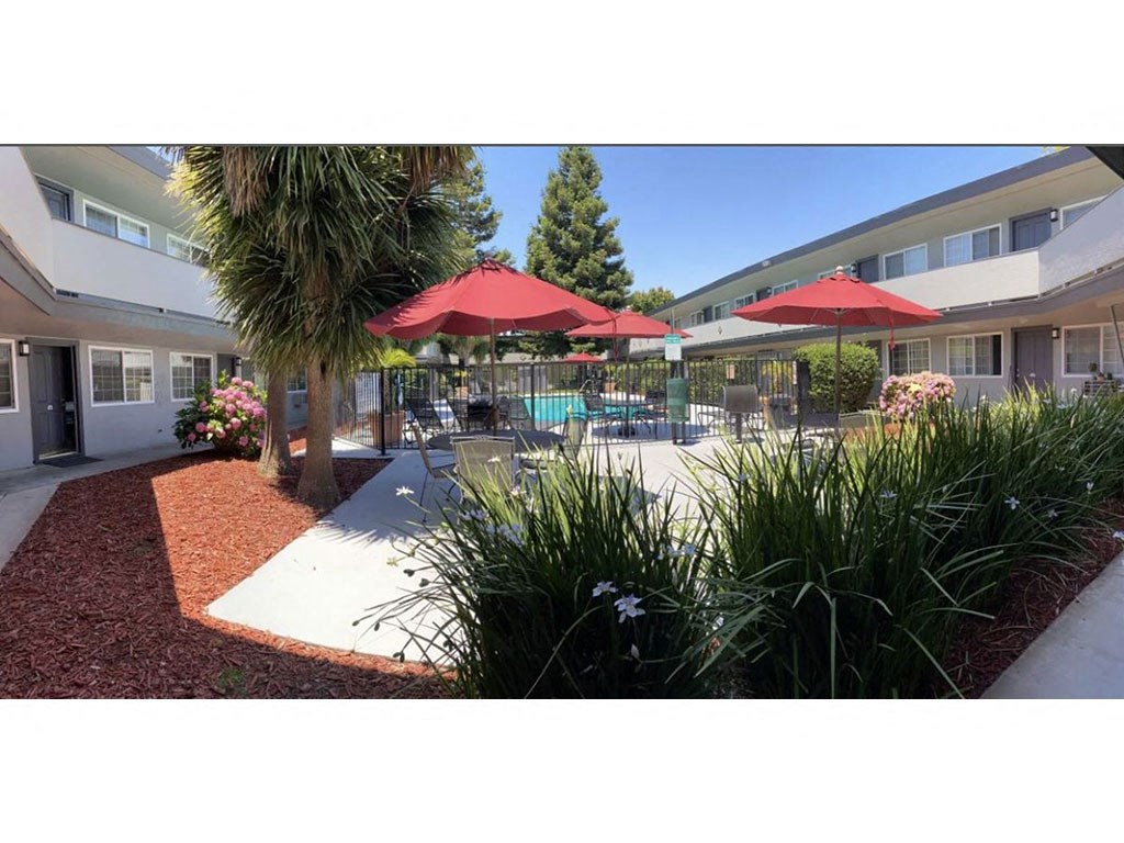 a patio with umbrellas and chairs in front of a building