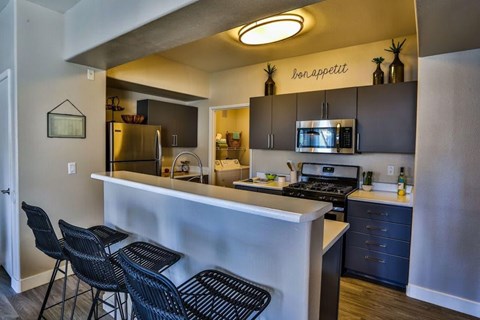 A kitchen with a bar area and chairs.