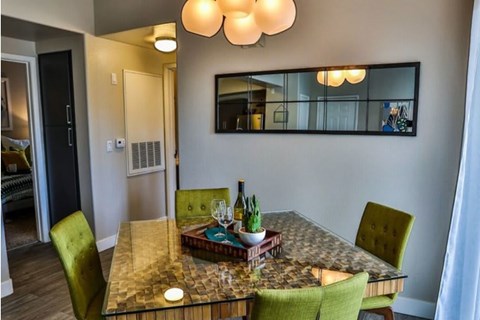 A dining room with a table set for two and a mirror on the wall.