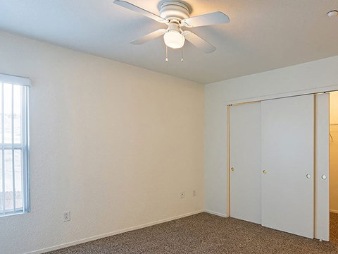 a bedroom with a ceiling fan and a closet