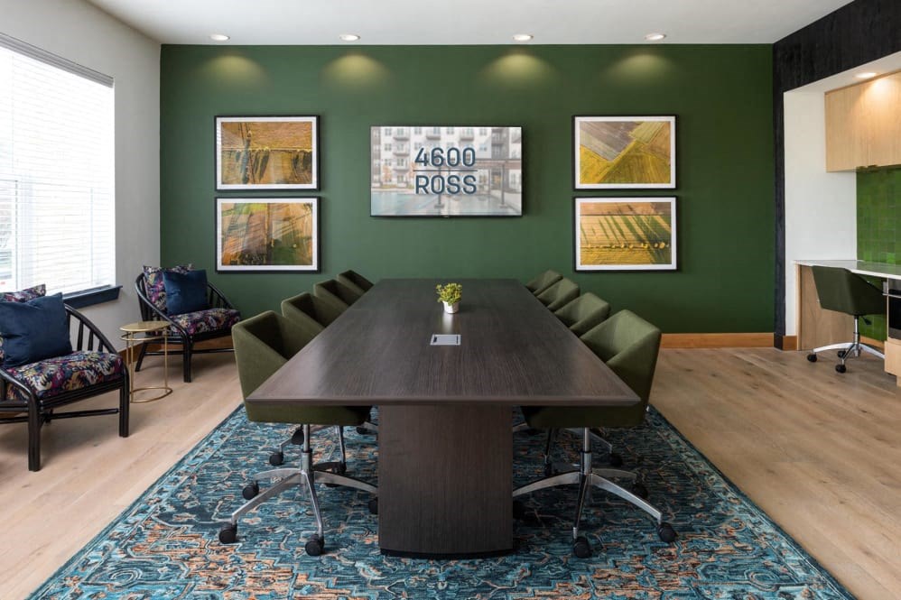 a conference room with green walls and a large wooden table with a vase of flowers on