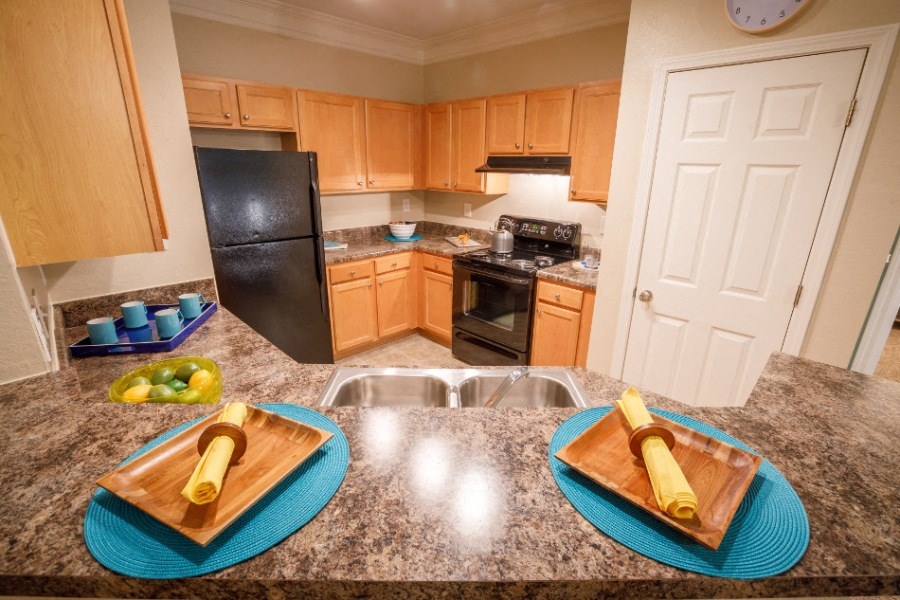 Classic kitchen with black appliances and an eating area at The Asher at Sugarloaf, a pet-friendly community in Lawrenceville, GA, near Duluth.