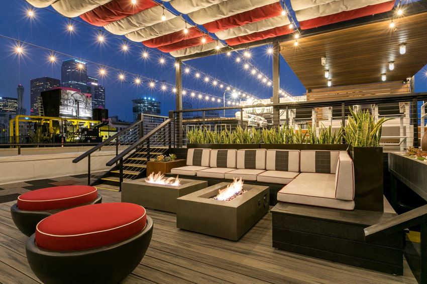 a rooftop deck with couches and fire pits and a view of the city at night - Photo Gallery 1