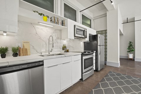 a white kitchen with stainless steel appliances and a sink
