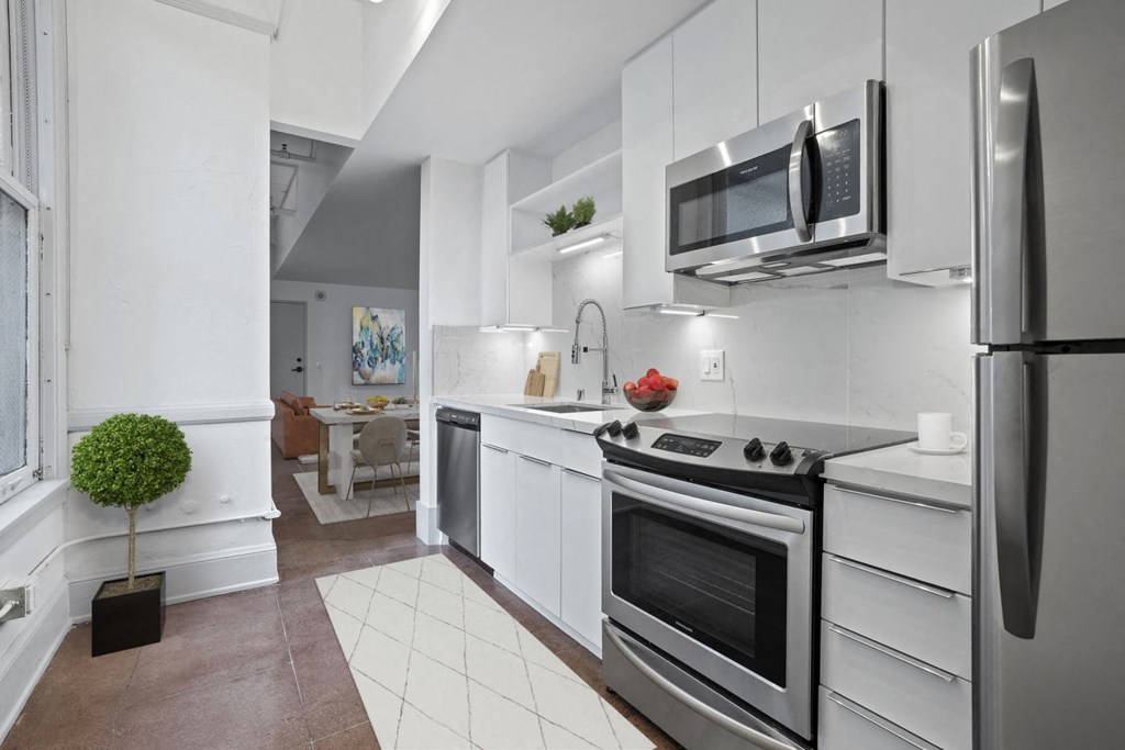 Downtown Los Angeles, CA Apartments - Santa Fe Lofts - Luxury Kitchen with Original Concrete Flooring and Hexagonal Plaster Detail, High Ceilings, Stainless Steel Appliances, White Cabinets, Marble Counters and Backsplash