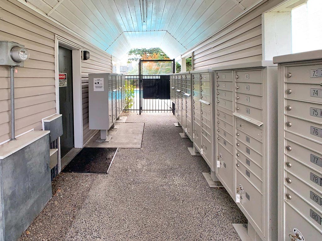 a long hallway with mailboxes and a gate