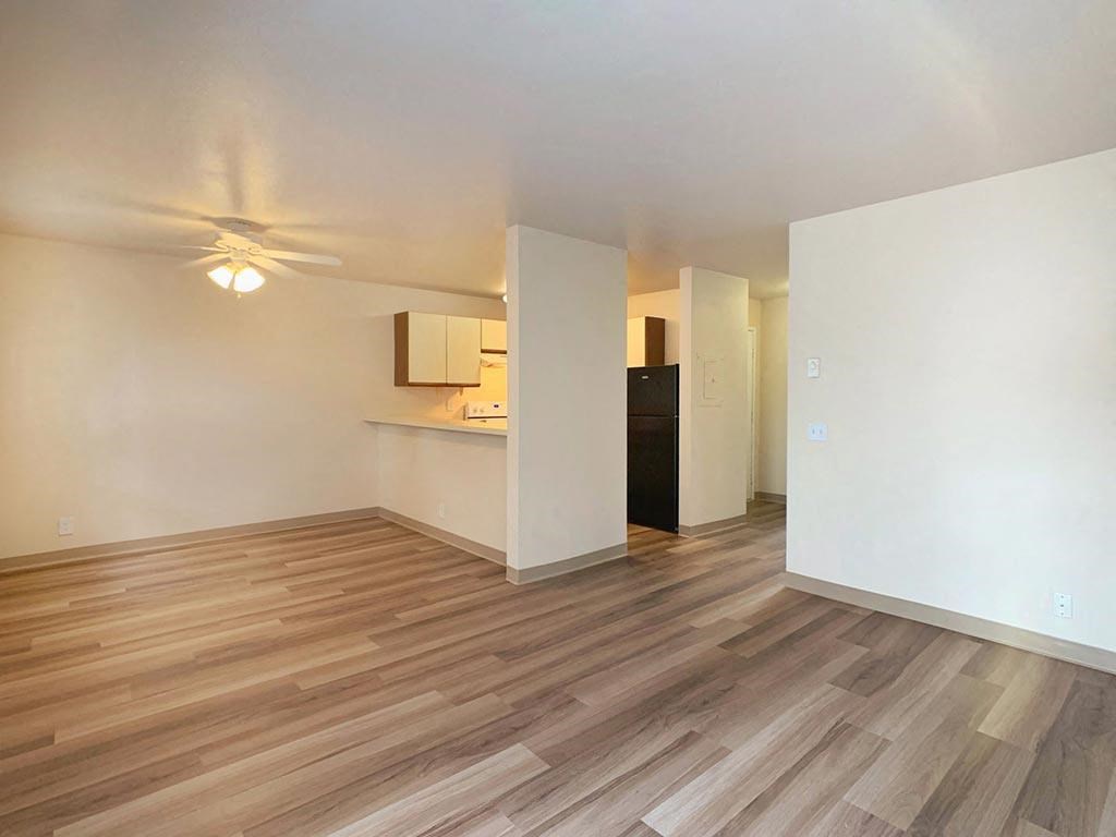 the living room and kitchen of an apartment with wood flooring