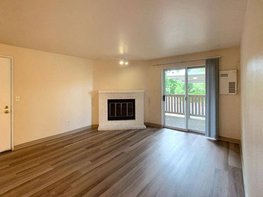 an empty living room with a fireplace and a sliding glass door
