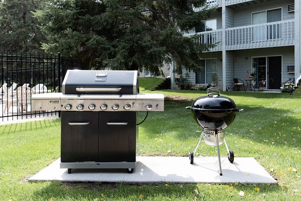 a grill and barbecue on a patio in a backyard