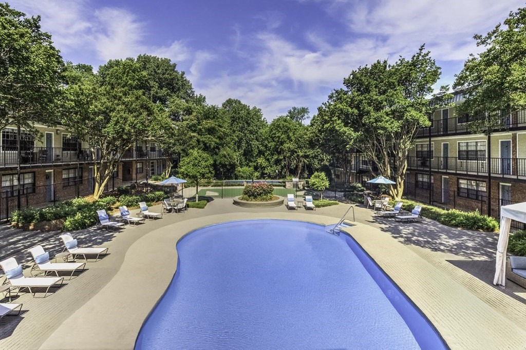 an outdoor pool with lounge chairs and umbrellas at an apartment building