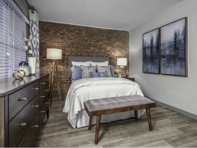 a bedroom with a brick wall and a bed and a bench