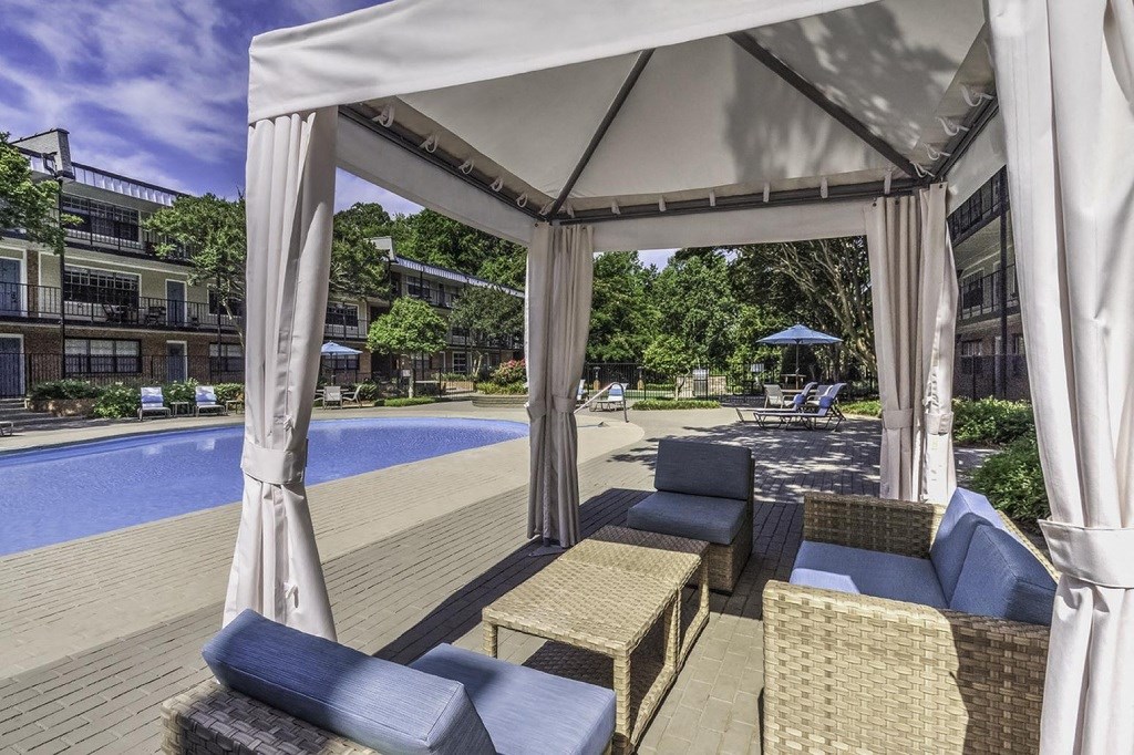 a canopy over a pool area with chairs and umbrellas