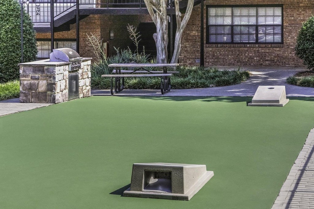 a green artificial lawn with a dog fountain and a picnic table