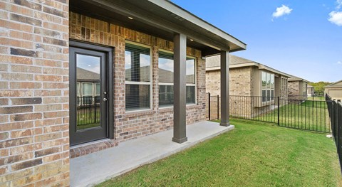 the front porch of a brick house with a black fence