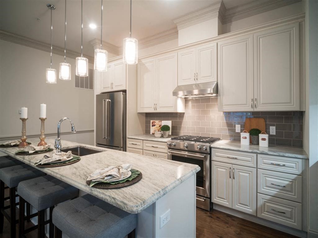 a kitchen with white cabinets and a marble counter top