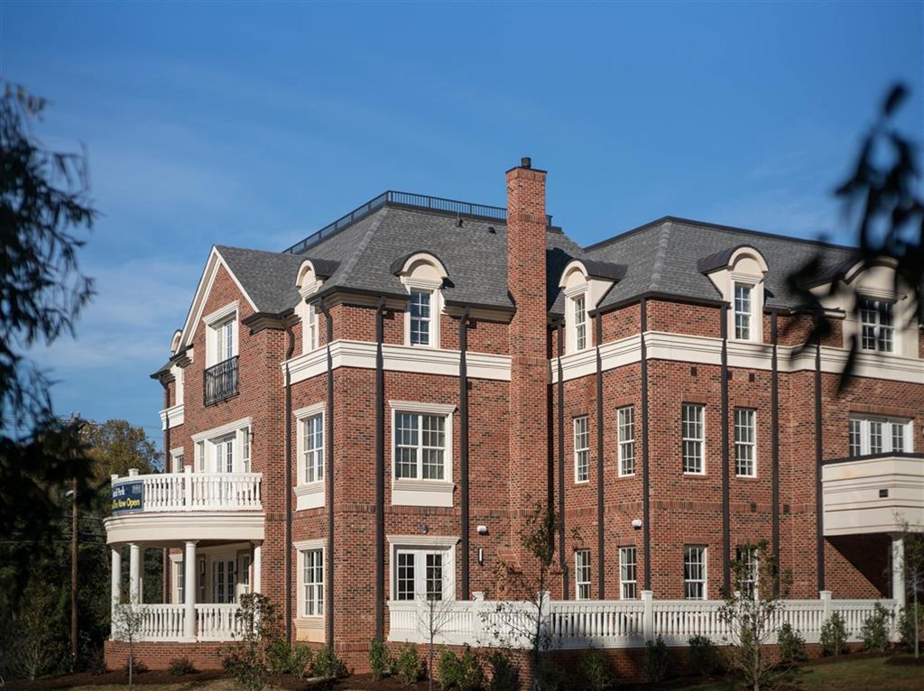 a large brick building with a gray roof and a white balcony