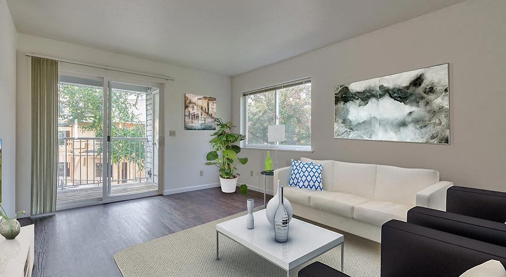 Coeur d' Alene, ID, Apartments For Rent - Living Room With Upgraded Wood-Style Flooring. Area Rug, Couch, Armchairs, Coffee Table, Wall Art, Houseplant, Window, And Sliding Glass Door With Balcony Access.