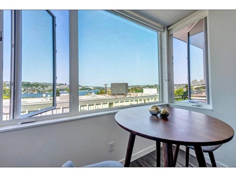Seattle, WA, Apartments Near Pike Market Place - Shelton Eastlake - Dining Area With Hardwood Floor, Round Table, Large Windows, and Stunning Lake Union and Seattle Skyline Views.