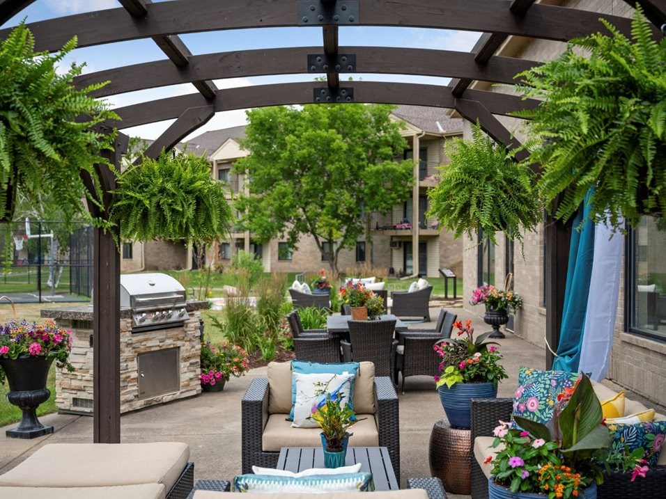 a covered patio with tables and chairs and a grill