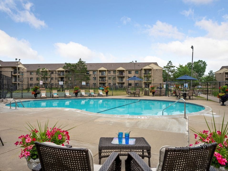a swimming pool with chairs and tables around it