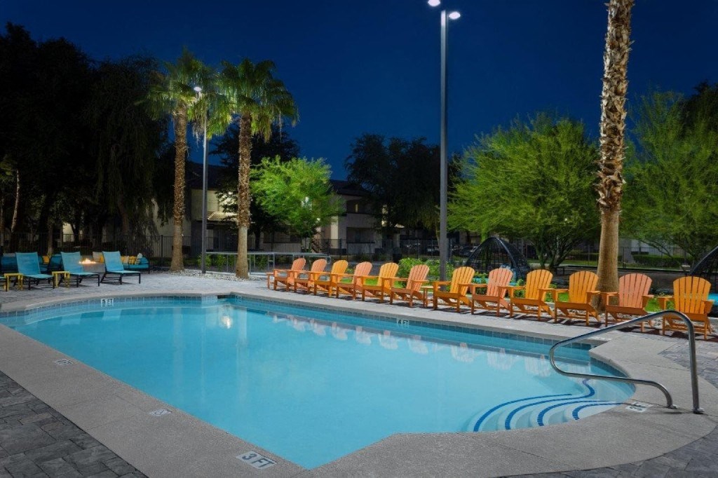 a swimming pool with yellow chairs around it at night