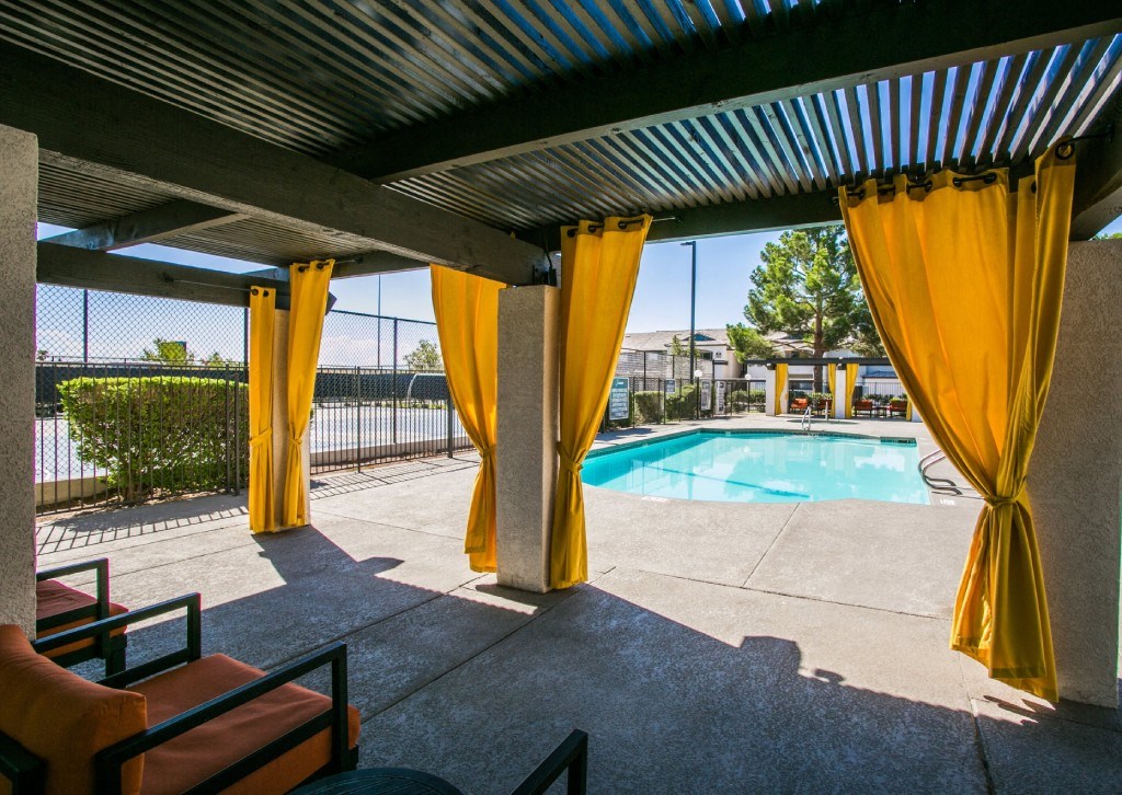 the pool is under a covered patio with yellow curtains