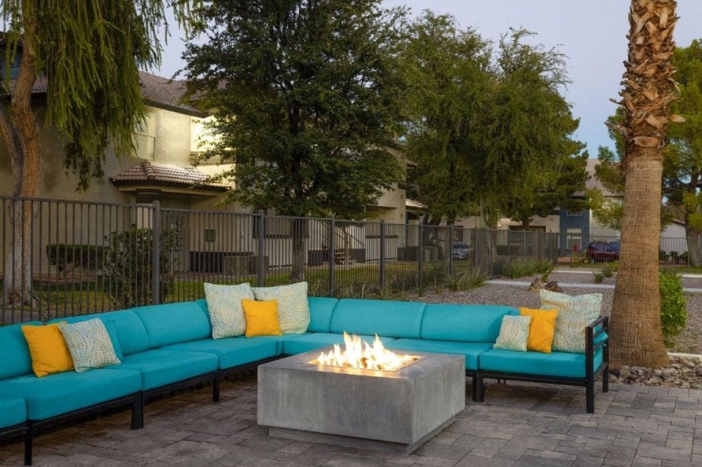 a patio with blue couches and a fire pit
